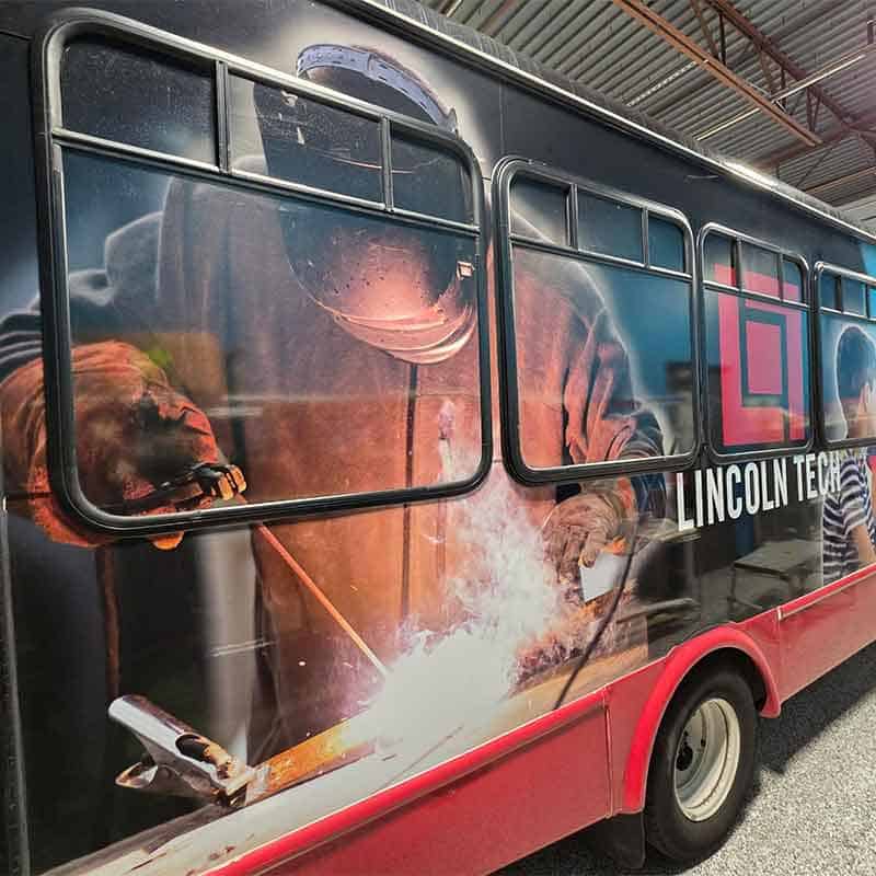 Vinyl vehicle wrap for Lincoln Tech made by Strategic Factory with blue collar worker on the side.